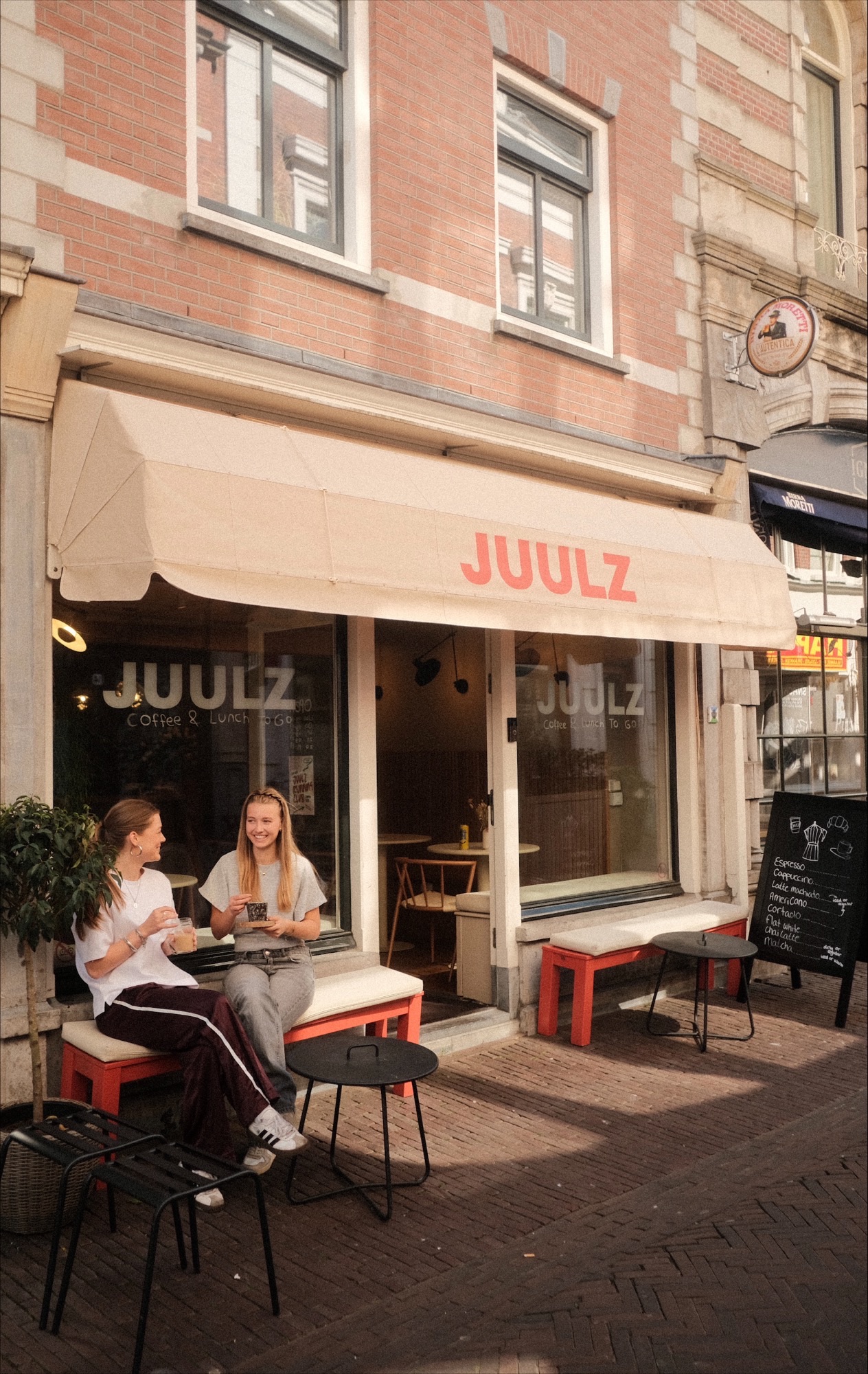 Two people drinking coffee outside a coffee bar